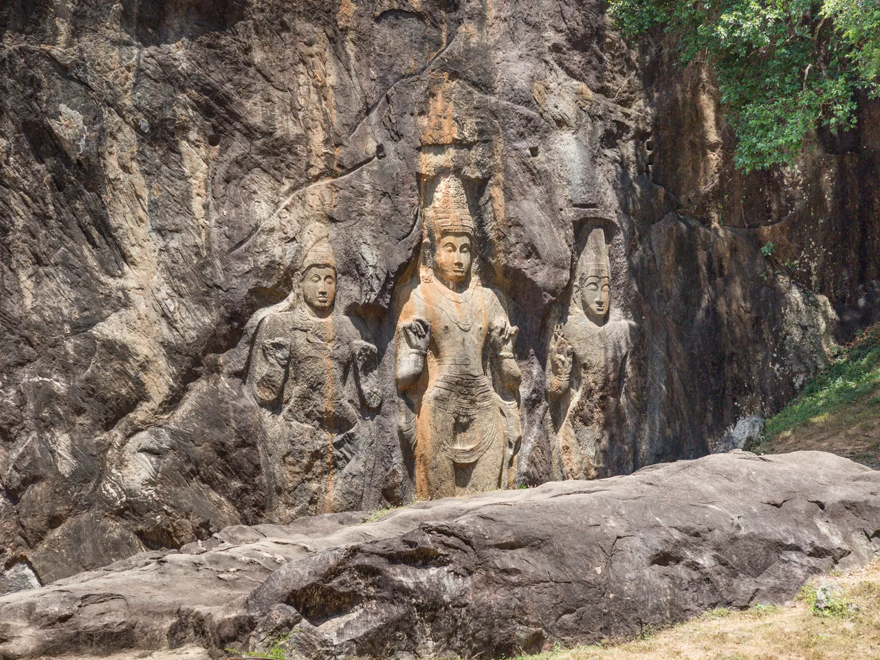 Buddha statues carved into the rock at the ancient Buduruwagala reliefs in Sri Lanka.
