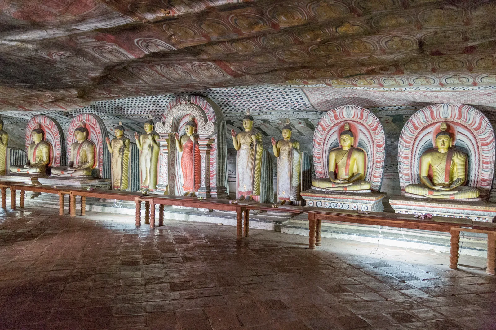 Ancient Buddha statues and colorful ceiling murals inside the Dambulla Cave Temples, Sri Lanka