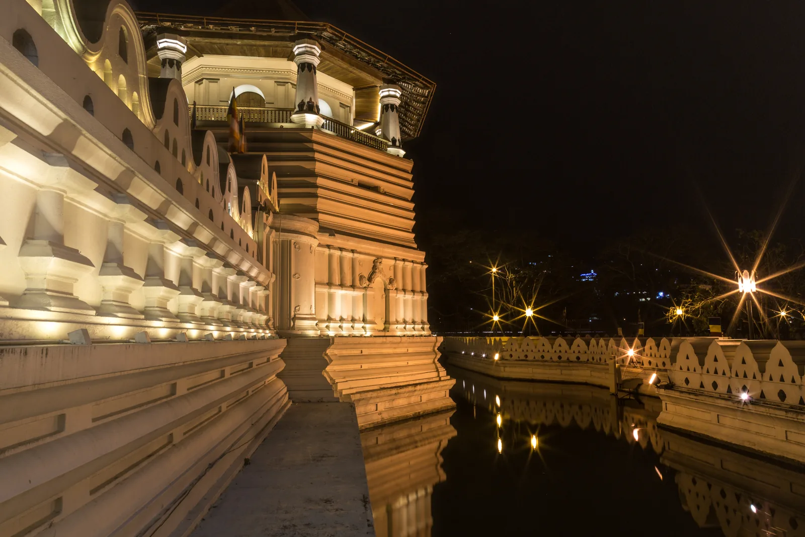 Temple of the Tooth Relic illuminated at night and reflected in the water in Kandy, Sri Lanka